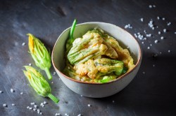 Zucchiniblüten in Bierteig in einer weißen Schale.