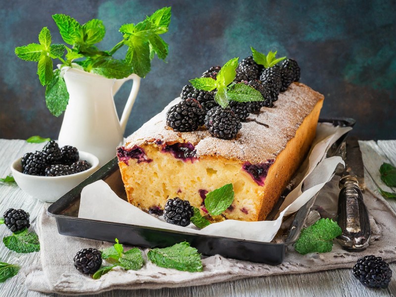 Brombeer-Joghurt-Kuchen auf einer Kuchenplatte, Minze