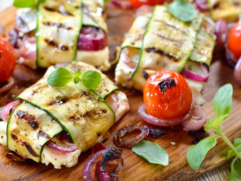 Holzbrett mit Feta-Zucchini-Päckchen vom Grill