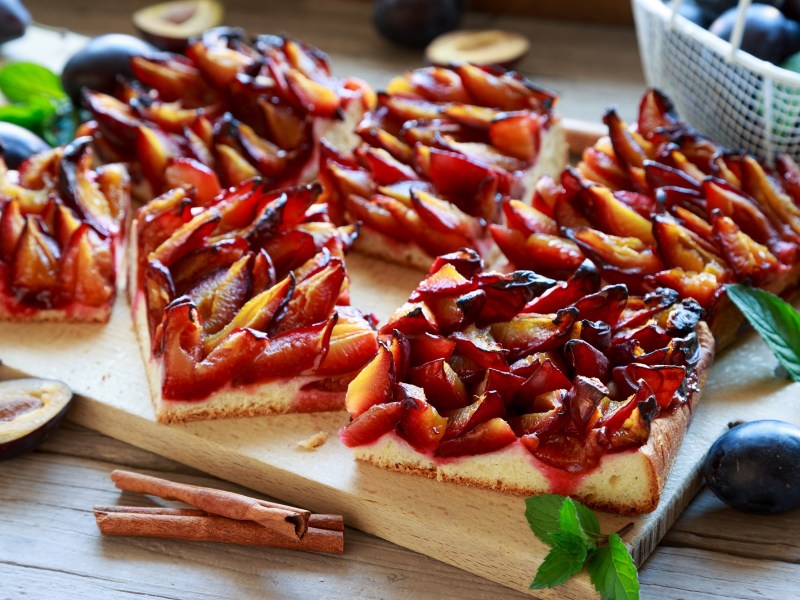 Einige Stücke Pflaumenkuchen mit Quark-Öl-Teig auf einem Brett.