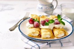 Ricotta-Pfannkuchen, garniert mit Himbeeren und Minze, auf einem Teller.