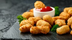 Tater Tots auf einer Marmorplatte mit einer Schüssel Ketchup.