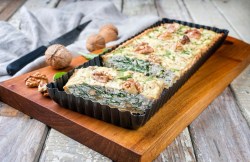 Eine Walnuss-Tarte mit Feta auf einem Holzbrett.