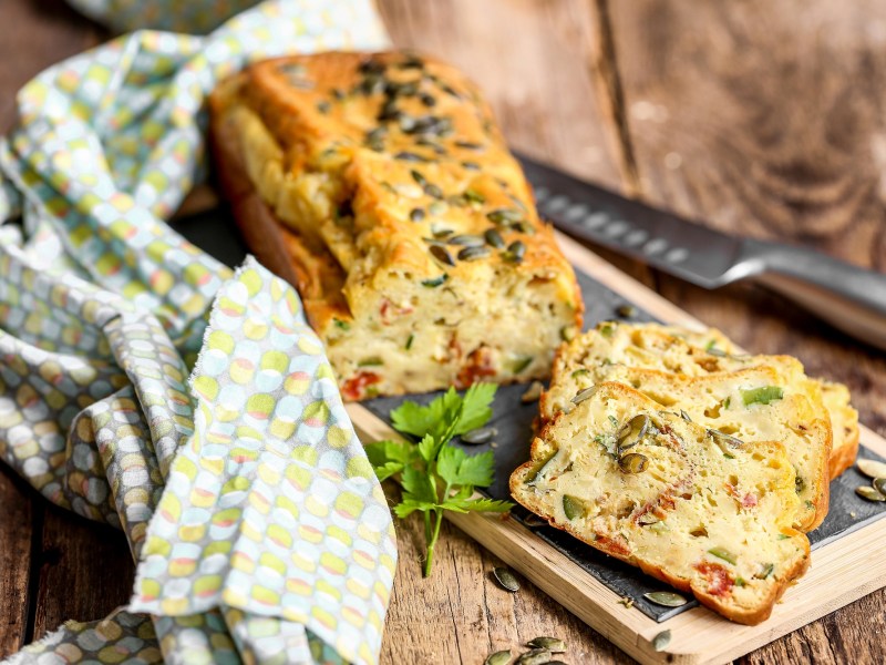 Zucchinibrot mit getrockneten Tomaten auf einem Holzbrett.