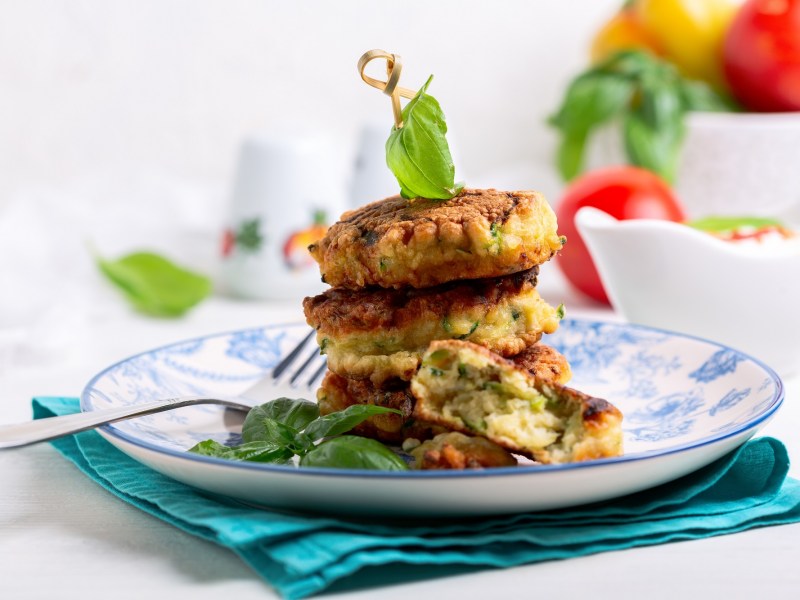 Zucchinipuffer mit Feta gestapelt auf einem Teller.