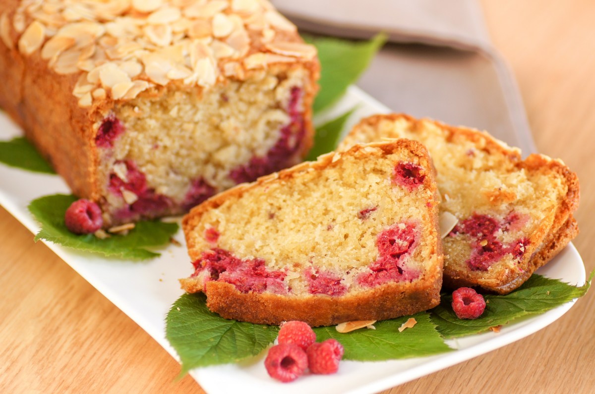 Ein angeschnittener Himbeer-Mandel-Kuchen auf einem Tisch.