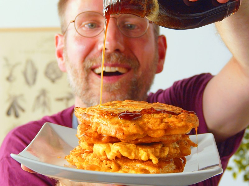 Ein Koch trÃ¤ufelt Sirup Ã¼ber einen Teller mit Kohl-Hackfleisch-Pancakes.