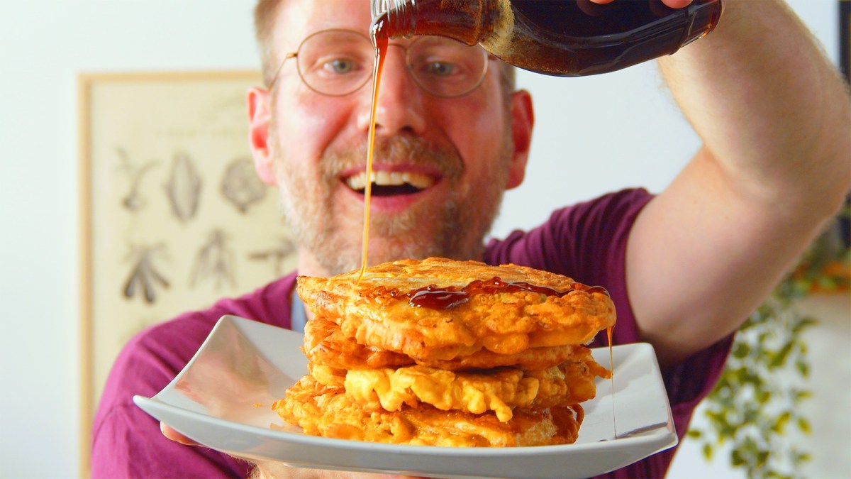 Ein Koch trÃ¤ufelt Sirup Ã¼ber einen Teller mit Kohl-Hackfleisch-Pancakes.