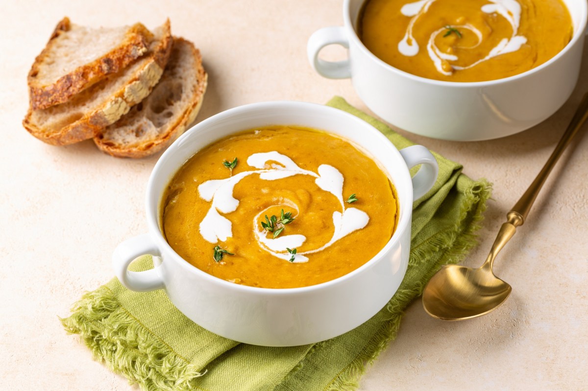 Zwei Schalen mit KÃ¼rbis-Linsen-Suppe auf einem Tisch.