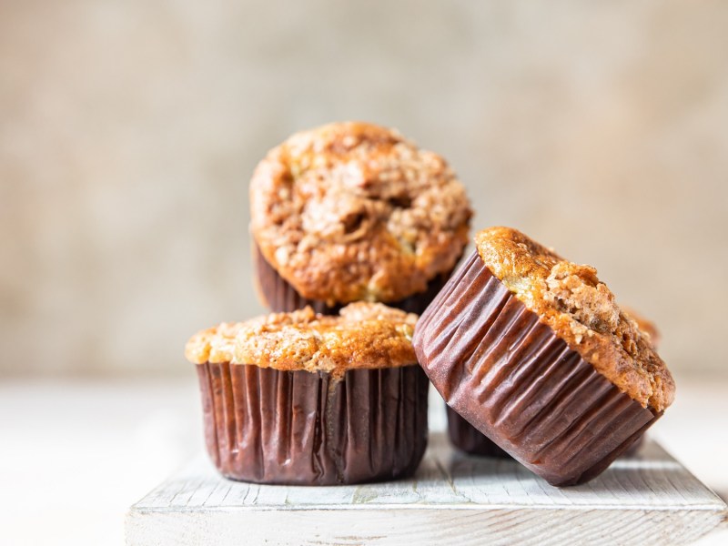 3 Kürbismuffins mit Streuseln in braunen Muffinförmchen.