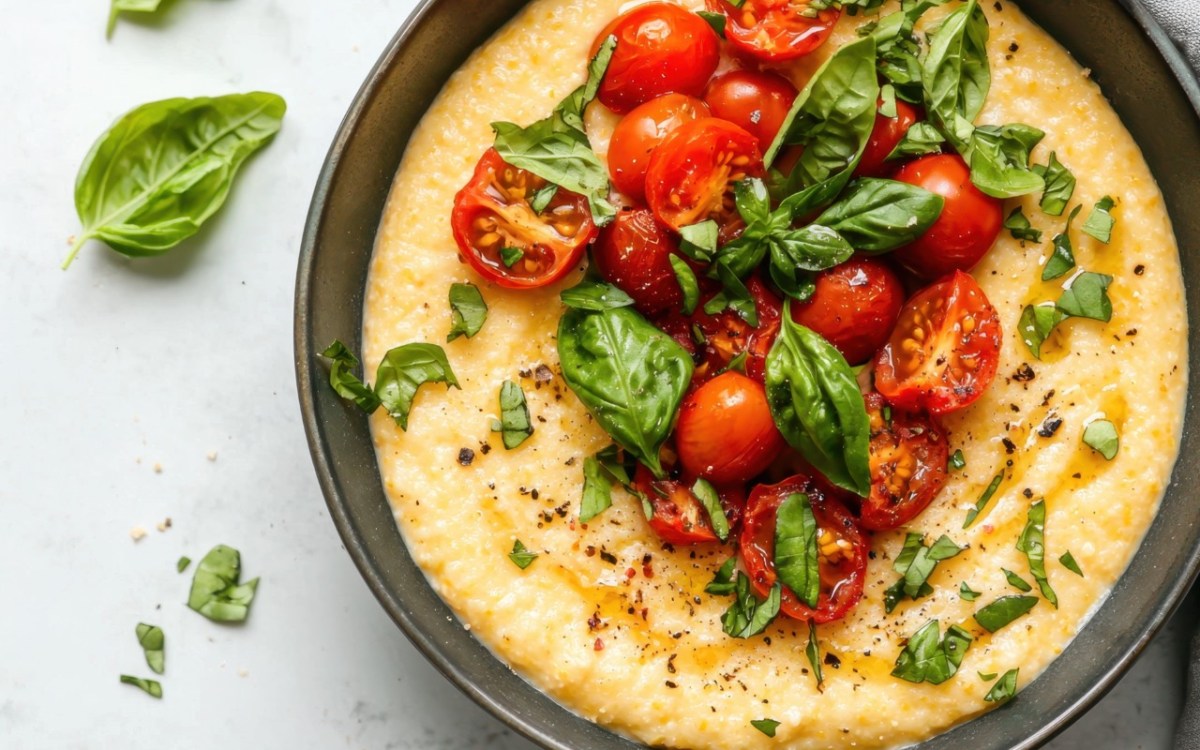 Eine SchÃ¼ssel mit Polenta mit Tomaten und Basilikum in der Draufsicht.