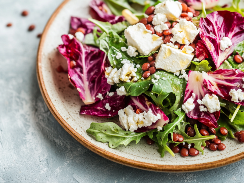 Ein Teller Rucola-Radicchio-Salat mit Linsen und FetawÃ¼rfeln. Nahaufnahme.