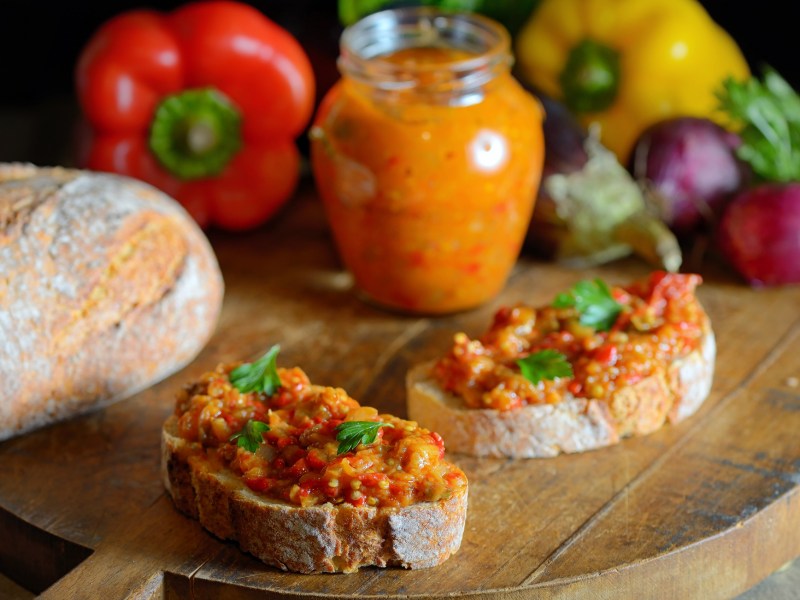 Zwei Scheiben Brot und ein Glas mit Zacusca.