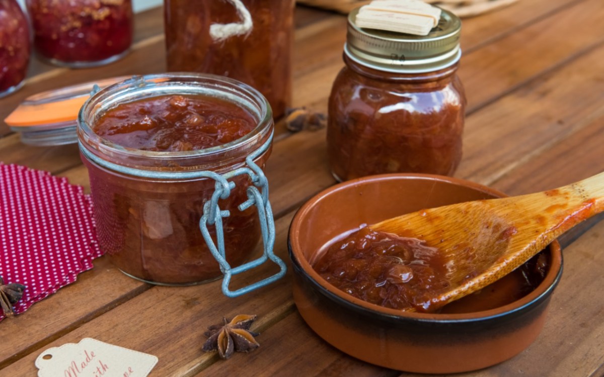 Mehrere GlÃ¤ser Zwetschgen-Chitney. Daneben ein HolzlÃ¶ffel mit Chutney, der in einer kleinen Schale liegt.