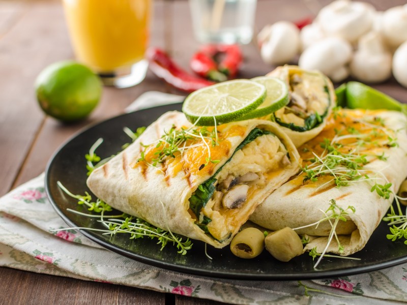 FrÃ¼hstÃ¼cksburrito mit Ei und Champignons auf einem Teller.