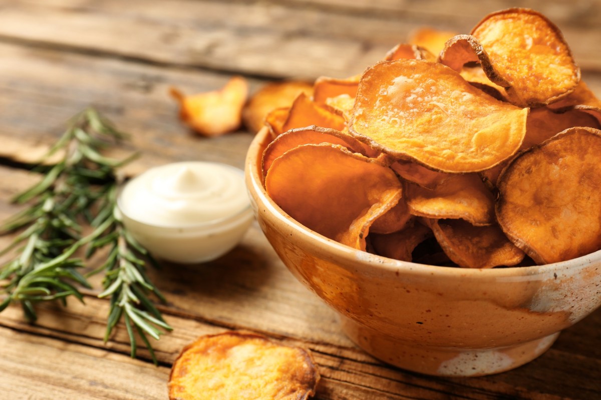 Eine SchÃ¼ssel KÃ¼rbis-Chips, daneben eine Schale mit weiÃŸem Dip und ein paar Rosmarinzweige.