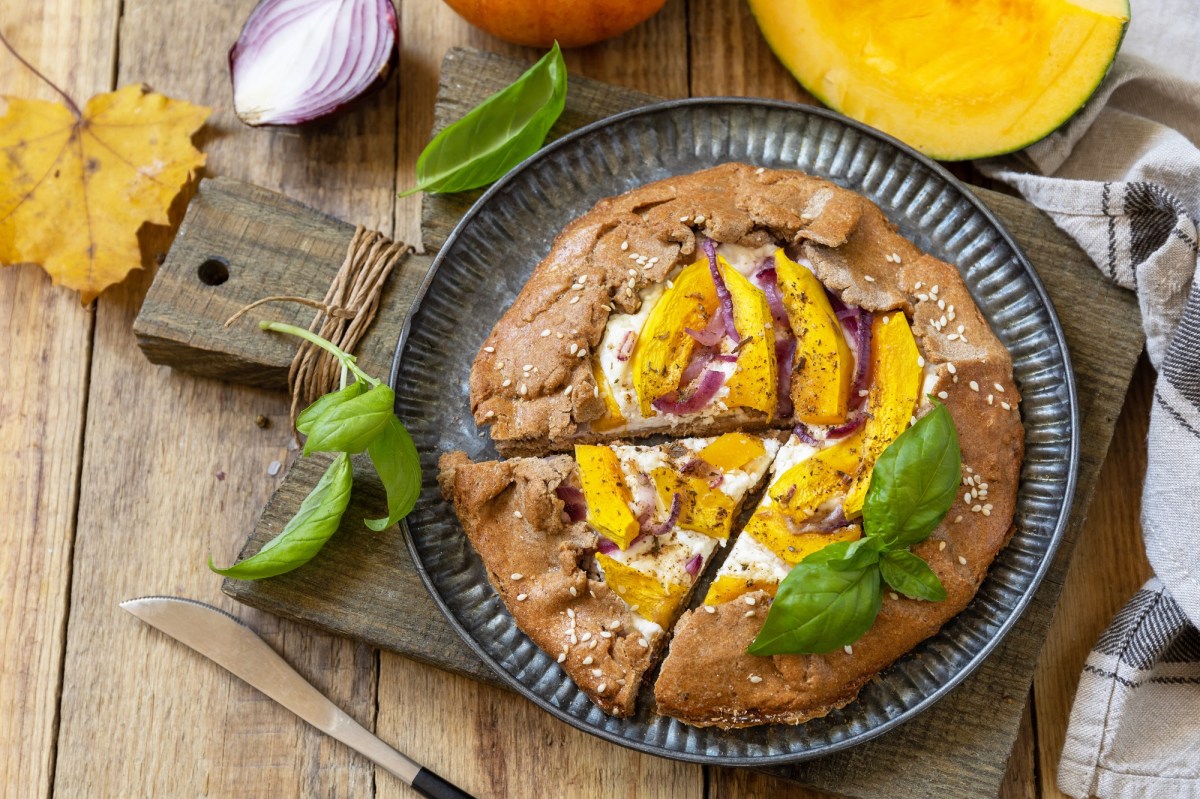 Eine KÃ¼rbis-Galette mit Ricotta auf einem Brett.