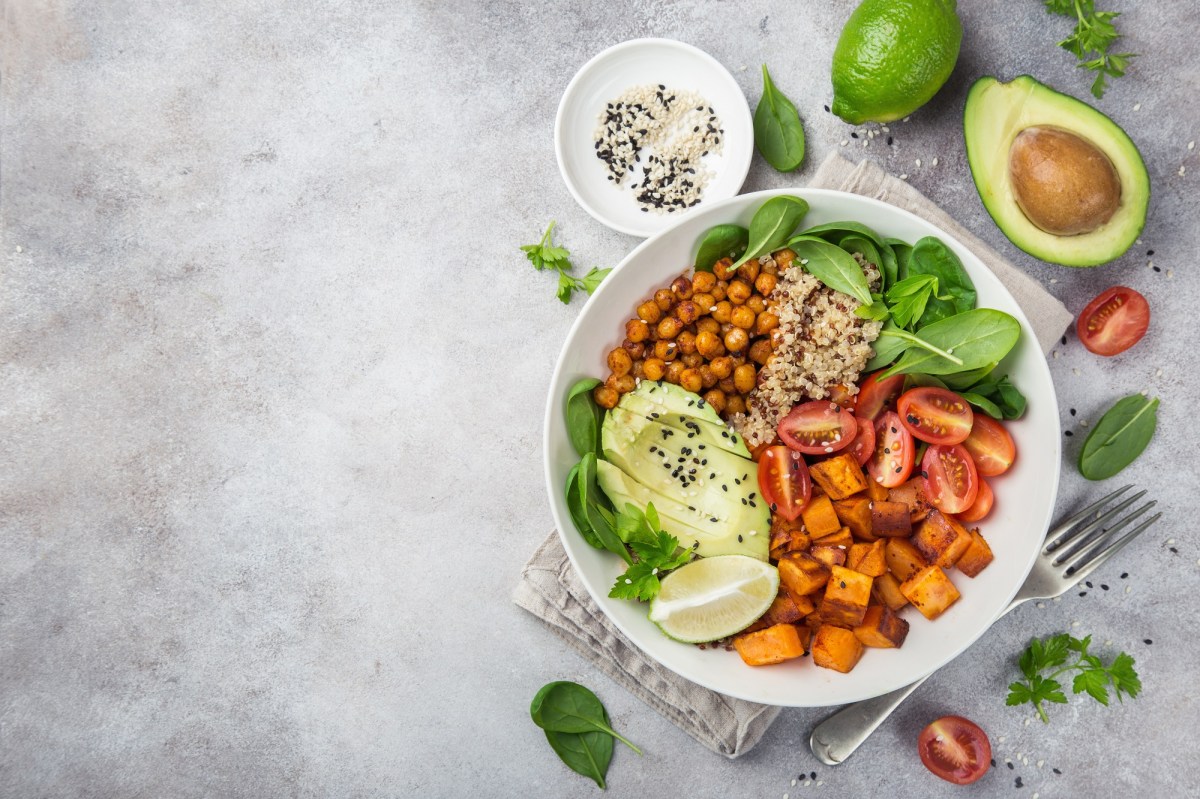 KÃ¼rbis-Quinoa-Bowl mit Kichererbsen und Avocado in der Draufsicht, drumherum Zutaten.