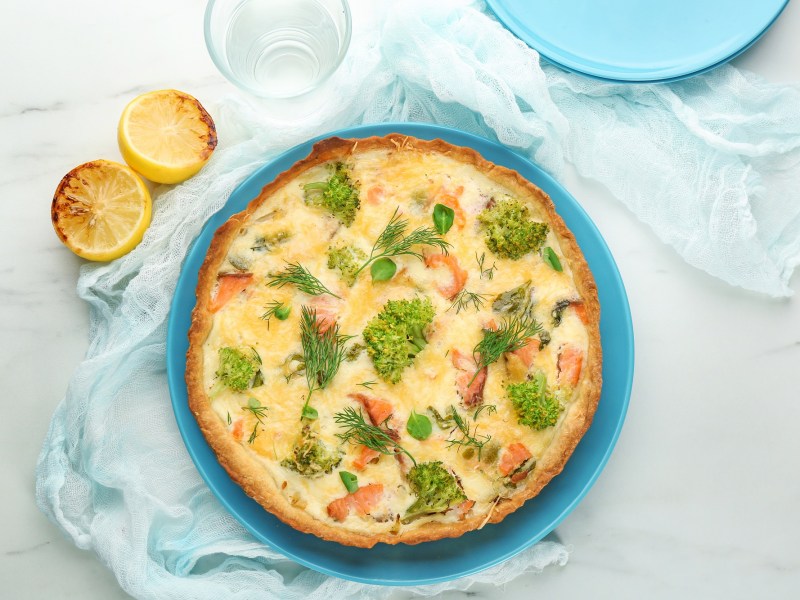 Lachs-Brokkoli-Quiche auf einem blauen Teller.