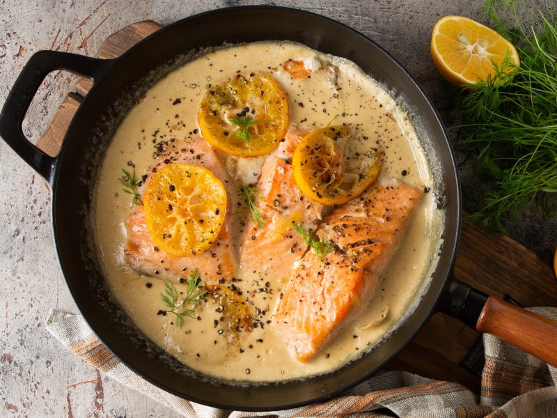 Lachs in Zitronen-SahnesoÃŸe in einer gusseisernen Pfanne.