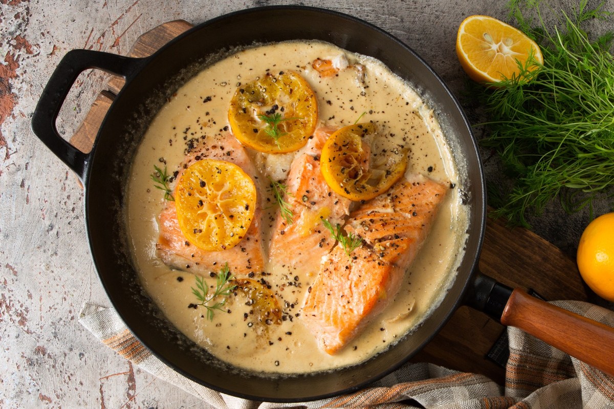 Lachs in Zitronen-SahnesoÃŸe in einer gusseisernen Pfanne.