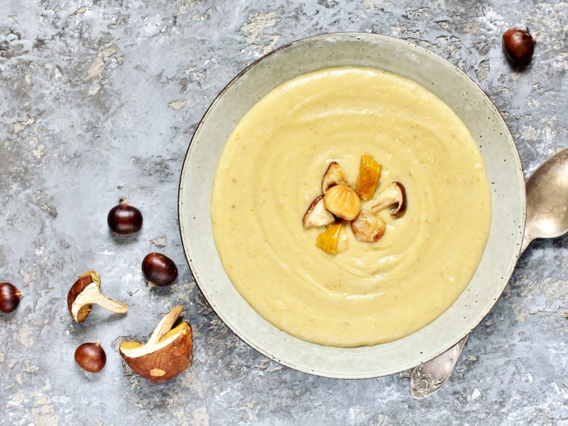 Ein Teller Maronen-Pilz-Suppe, garniert mit Esskastanien und Pilzen.