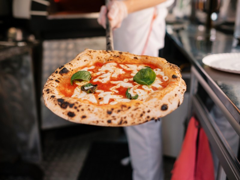 Perfekte Pizza: Ein PizzabÃ¤cker prÃ¤sentiert eine fertige Pizza.