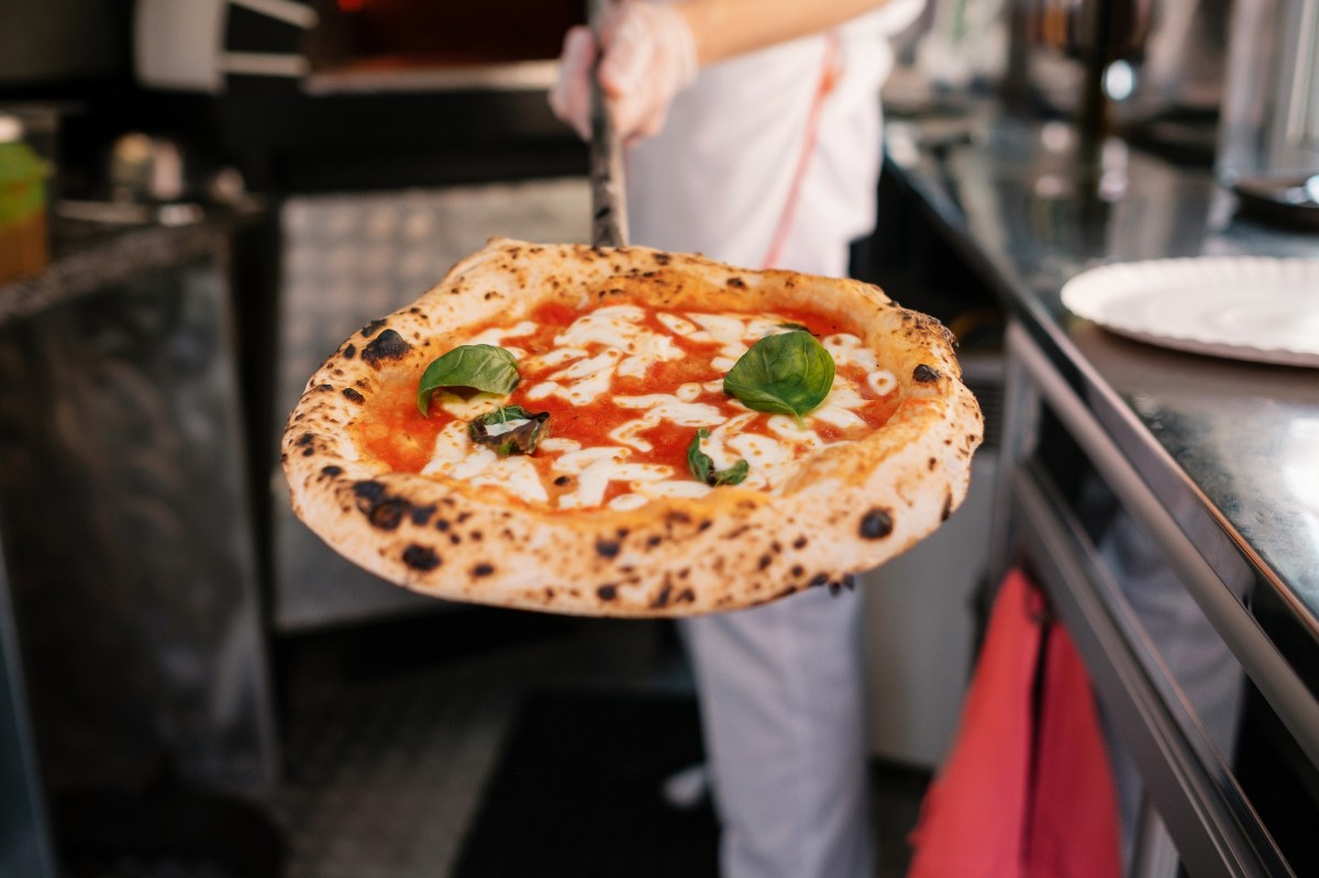 Perfekte Pizza: Ein PizzabÃ¤cker prÃ¤sentiert eine fertige Pizza.