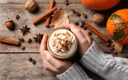 Pumpkin Spice selber machen: Eine Frau hält eine Tasse Kaffe mit Pumpkin Spice in den Händen. Drumherum liegen Zutaten.