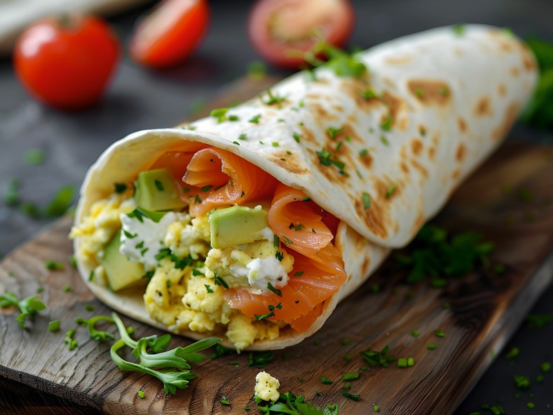 RÃ¼hrei-Wrap mit Lachs und Avocado auf einem Brett