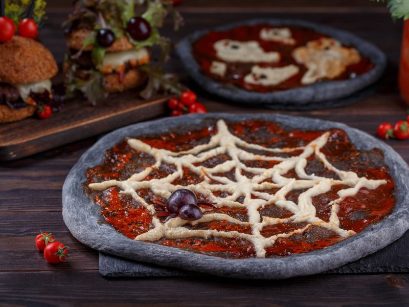 Eine schwarze Halloween-Pizza mit Spinnennetz.