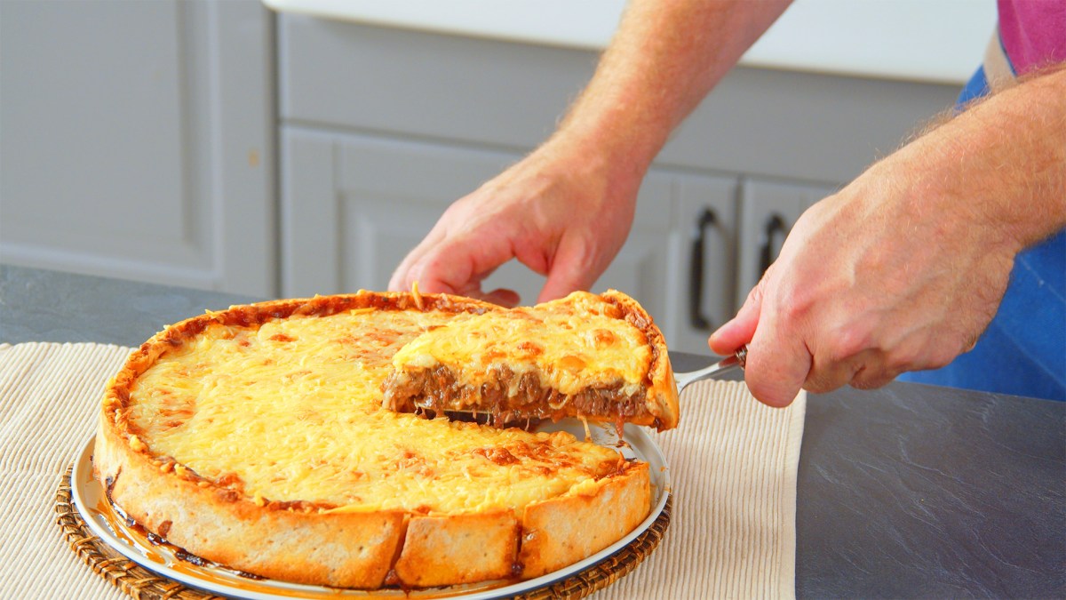 TiefkÃ¼hlpizza-Kuchen, aus dem ein StÃ¼ck herausgenommen wird.