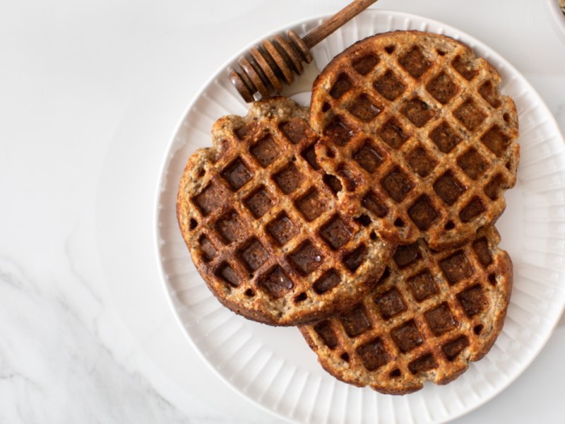 Drei Apfel-Müsli-Waffeln auf einem Teller in der Draufsicht.