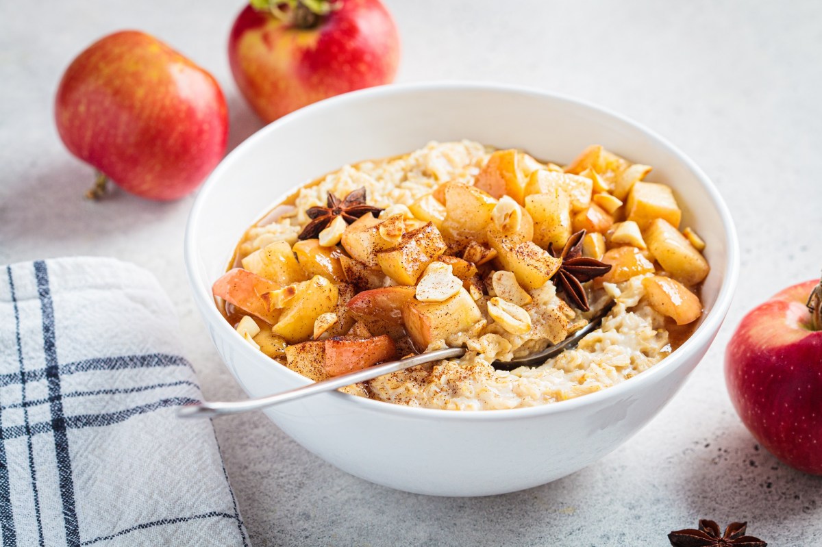 Eine Schale Bratapfel-Porridge mit gebratenen Ã„pfeln und Anissternen, drumherum Ã„pfel.