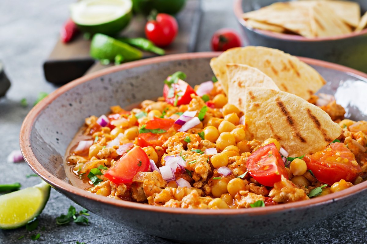 Eine ServierschÃ¼ssel mit Chili con Carne mit KÃ¼rbis und Tortillas.