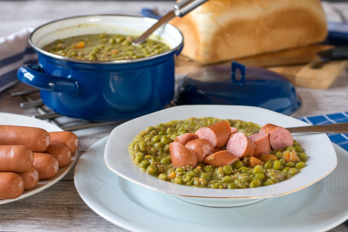 Ein Topf und ein Teller Erbsensuppe mit WÃ¼rstchen.