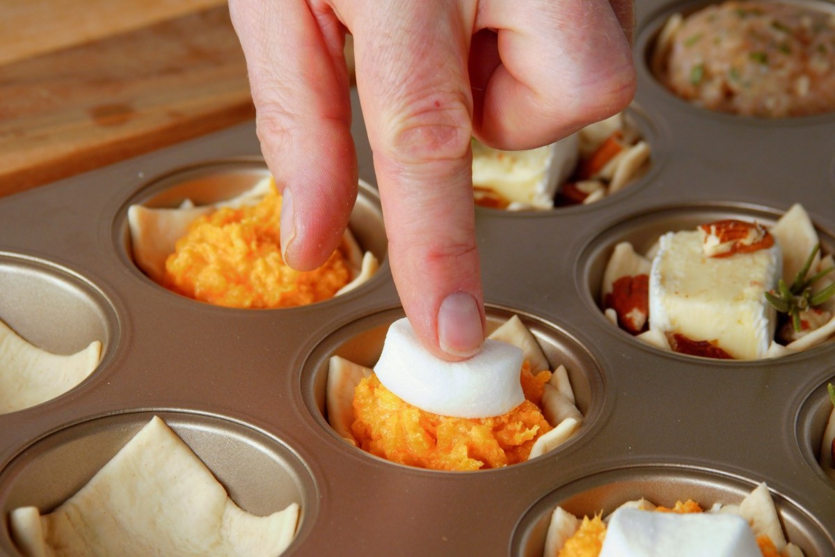 Fingerfood-Cups: Ein Marshmallow wird auf Kartoffelbrei aus SÃ¼ÃŸkartoffel in einem Muffinblech gedrÃ¼ckt.