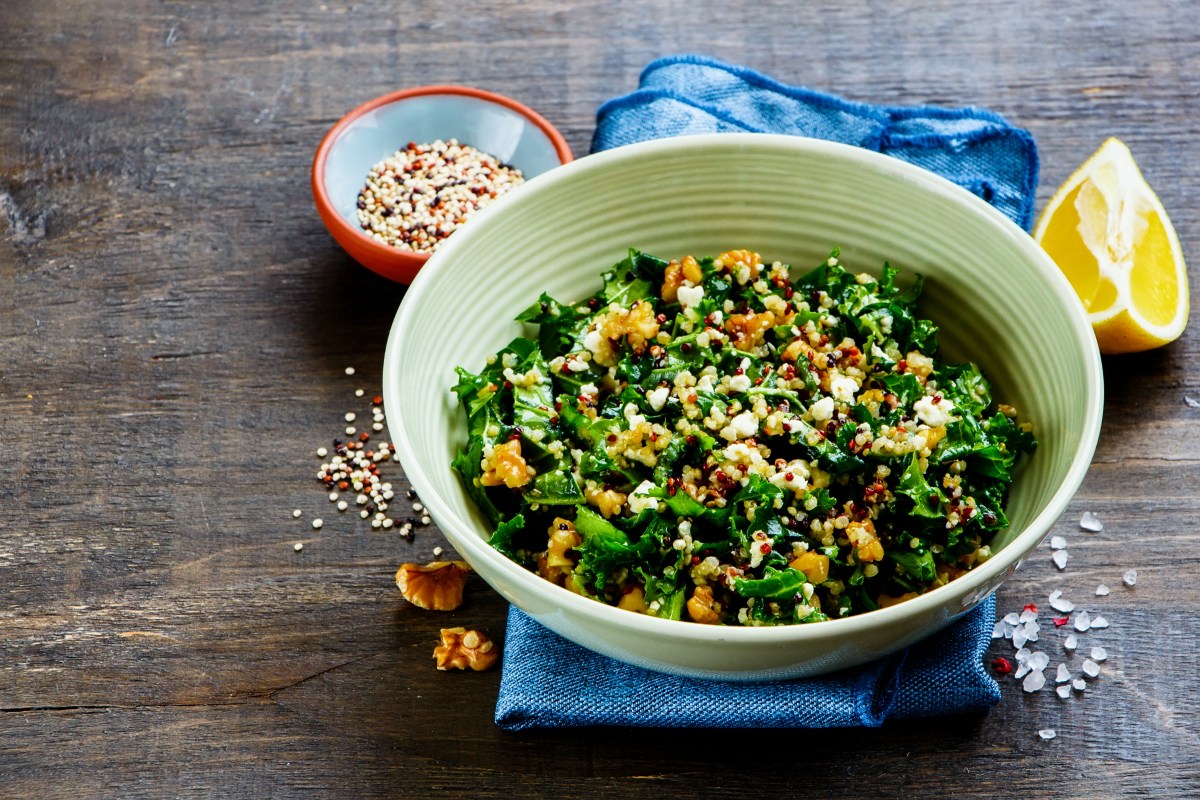 Eine SchÃ¼ssel GrÃ¼nkohlsalat mit Feta und WalnÃ¼ssen, daneben eine angeschnittene Zitrone.