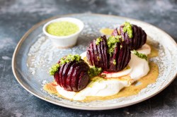 3 Hasselback-Rote-Beten auf einem Teller, garniert mit Kräutersoße und Joghurt.