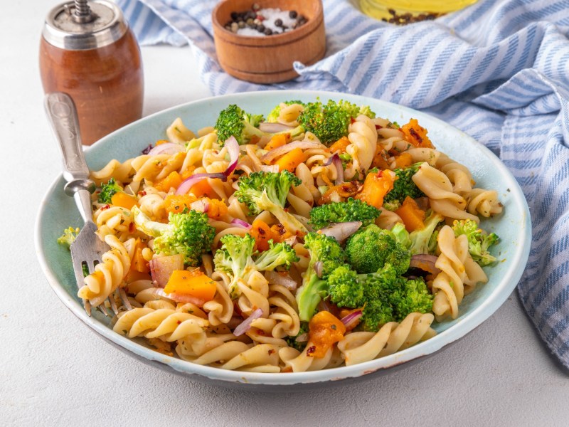 Herbstlicher Nudelsalat mit Brokkoli und KÃ¼rbis auf einem tiefen Teller.