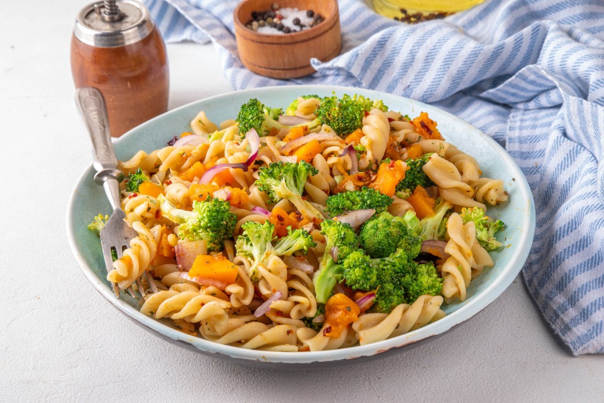 Herbstlicher Nudelsalat mit Brokkoli und KÃ¼rbis auf einem tiefen Teller.