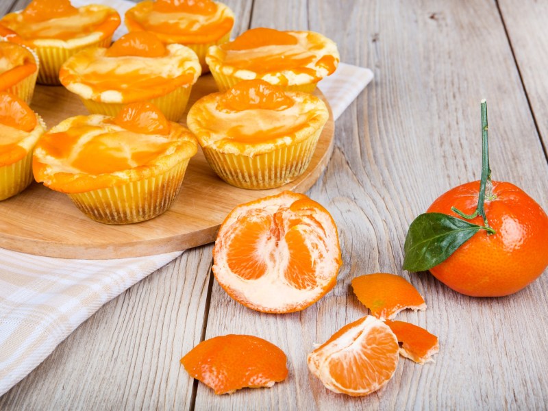 Käsekuchen-Muffins aus der Heißluftfritteuse, davor eine frische Mandarine.