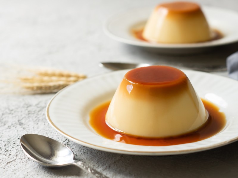 Zwei Karamell-Flan auf je einem kleinen Teller. Drum herum ist KaramellsoÃŸe zu sehen.