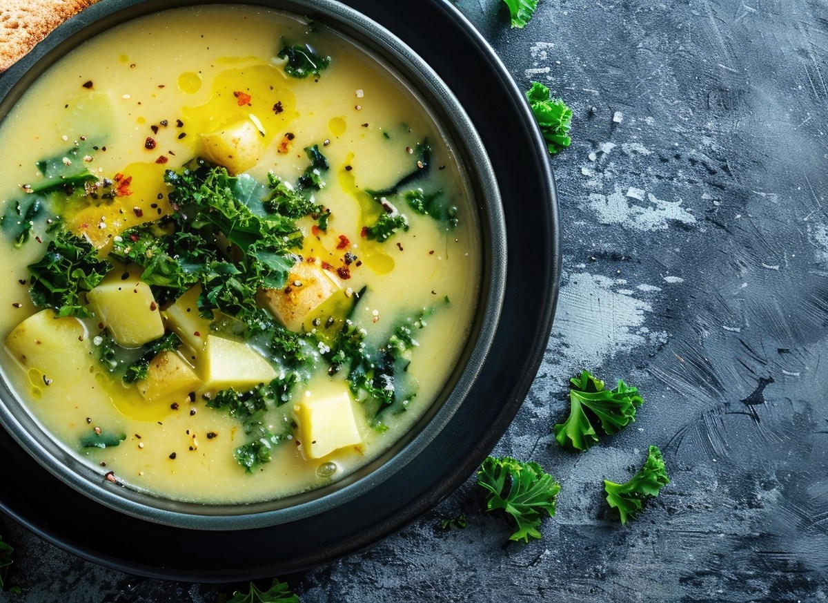 Schale mit Kartoffelsuppe mit Grünkohl, Brot daneben.