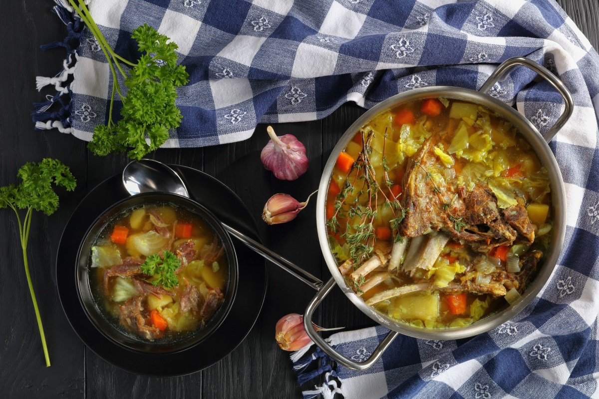 Ein Topf und eine Schale KjÃ¶tsupa: islÃ¤ndische Lammsuppe mit Kohl auf einem karierten Geschirrtuch.