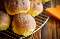 Mehrere Kürbis-Buttermilchbrötchen auf einem Kuchengitter.