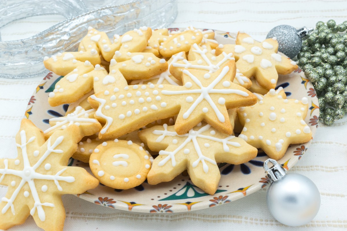 Ein Teller MarzipanplÃ¤tzchen verziert mit Zuckerguss, daneben Weihnachtsdeko.