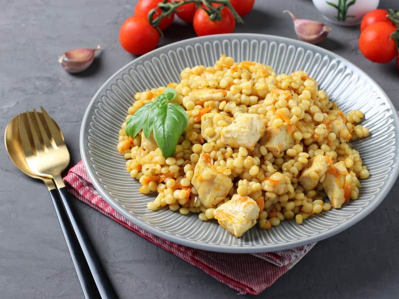 Perlcouscous mit HÃ¤hnchen auf einem Teller.