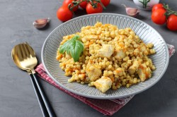 Perlcouscous mit Hähnchen auf einem Teller.