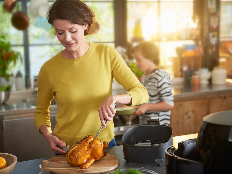 Philips Airfryer XL Black Friday Amazon: Frau kocht mit HeiÃŸluftfritteuse ein Huhn.